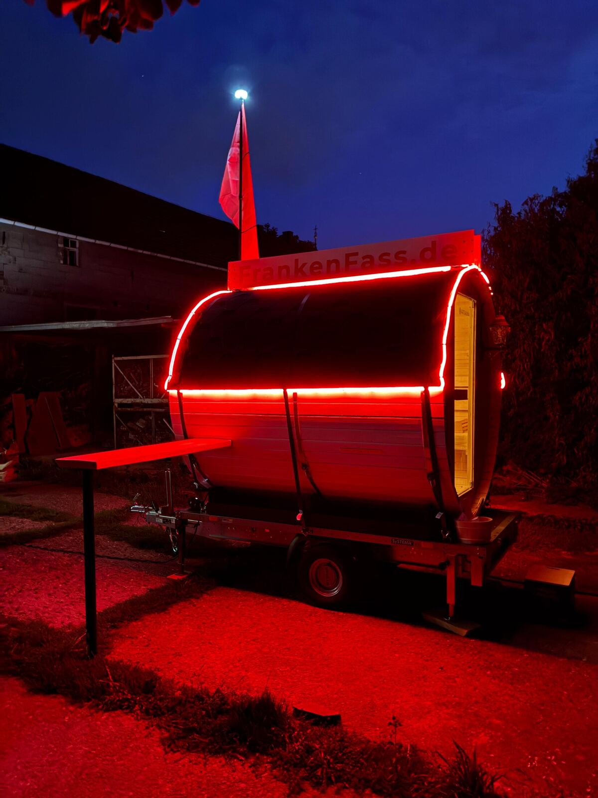 Mobile FrankenFass Fasssauna bei Nacht mit stimmungsvoller roter LED-Beleuchtung